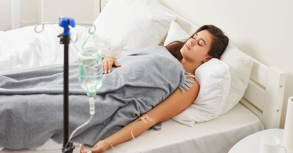 Woman resting in bed receiving IV hydration therapy at a clinic in Medford, OR