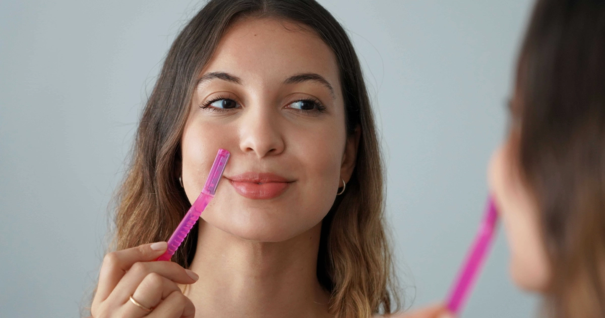 Young woman using a pink dermaplaning tool near her upper lip during Dermaplaning in Medford, OR.